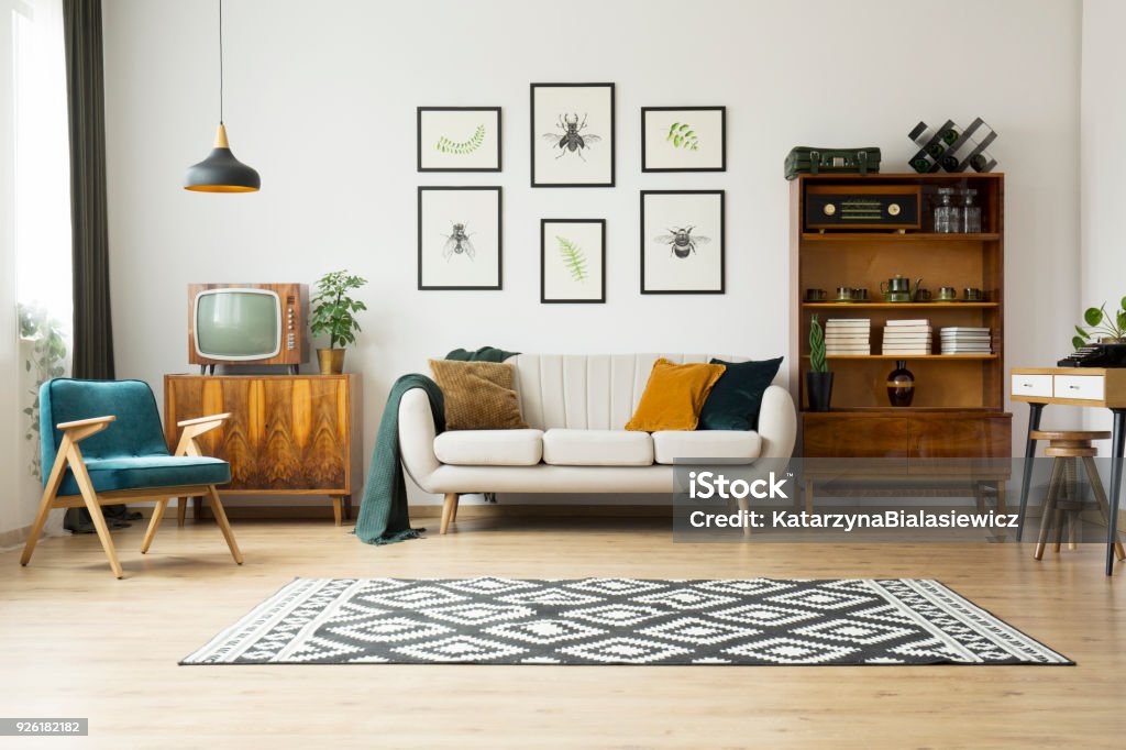 Vintage tv next to couch Vintage tv standing on a wooden cabinet next to a comfy couch in a stylish day room interior Living Room Stock Photo