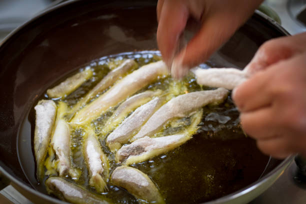 istock Italian Cuisine: Hands Putting Small Fish to Fry in Pan 926182842
