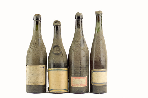 four different  dusty bottles of old wine  lined on white background