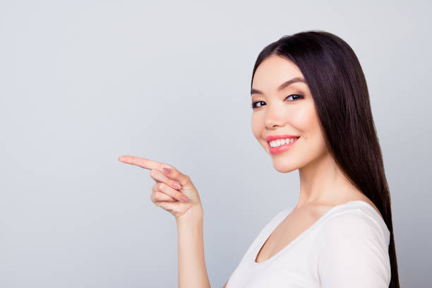 istock Successful, pretty, smiling, charming  woman  on grey background  is pointing  with her fingers 926189908