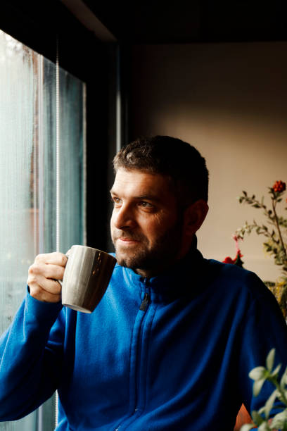 istock Portrait of man holding coffee cup by window 926194214