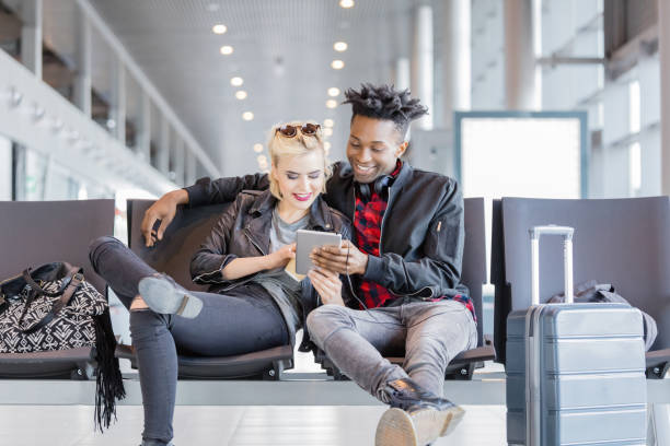 istock Young funky couple using digital tablet in airport lounge 926196394