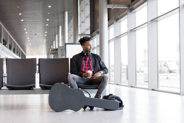 Funky young man waiting for flight in airport lounge