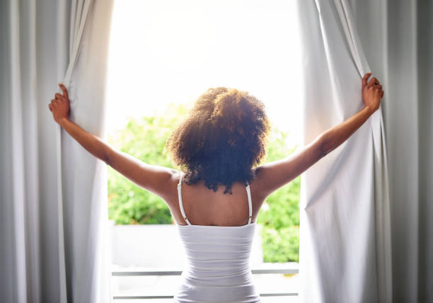 Good morning world! Rearview shot of an unrecognizable woman opening her bedroom curtains after waking up from sleeping routine stock pictures, royalty-free photos & images