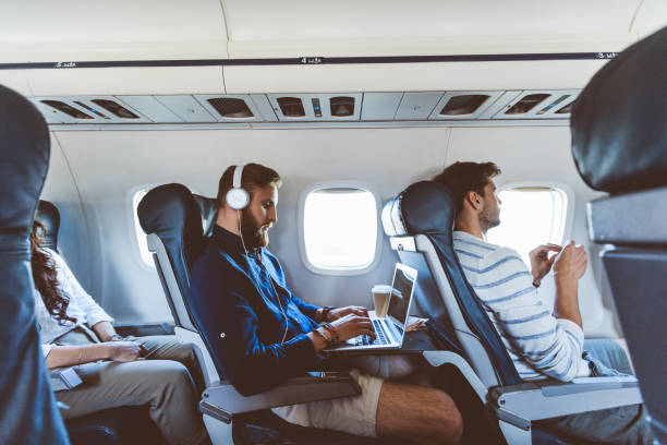 männlichen passagier mit laptop während des fluges - economy class stock-fotos und bilder