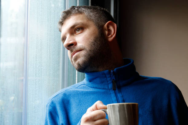 istock Portrait of man holding coffee cup by window 926208258