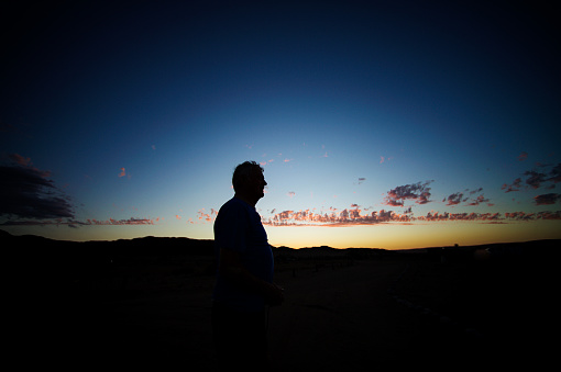 The silhouette of a 70-79 year old against a vibrant color sunset Namib Rand Namibia Africa