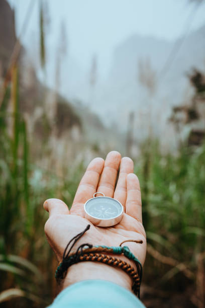 istock Man arm with compass on the palm stretched out to determine position in mountains on cloudy day 926215342