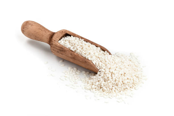 Basmati rice in a serving scoop shot on white background Wooden serving scoop filled with basmati rice isolated on white background. Some grains are out of the scoop spilled directly on the table. DSRL studio photo taken with Canon EOS 5D Mk II and Canon EF 70-200mm f/2.8L IS II USM Telephoto Zoom Lens rice cereal plant stock pictures, royalty-free photos & images