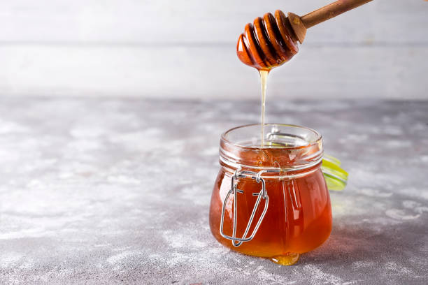 istock Spoon of honey with jar on a light background 926219930