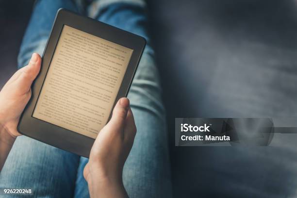 Girl Is Reading Ebook While Relaxing On The Sofa Stock Photo - Download Image Now - E-Reader, Reading, Book