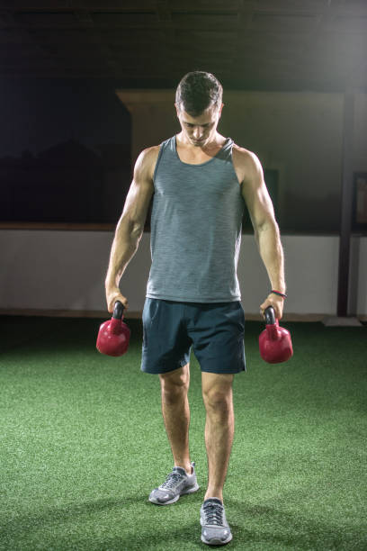 homem musculoso, segurando os sinos chaleira e preparando-se para o treinamento de peso. - weights men weight picking up - fotografias e filmes do acervo