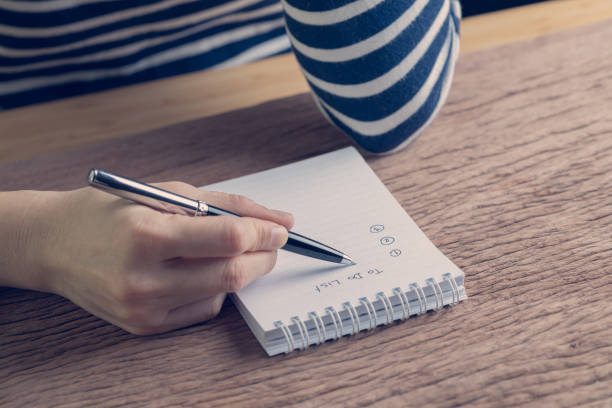 mano femenina con pluma escribir plan de negocios para la lista en tabla de madera en color vintage efecto, prioridad de la tarea y trabajo o día a día organizar - to do list checklist personal organizer writing fotografías e imágenes de stock