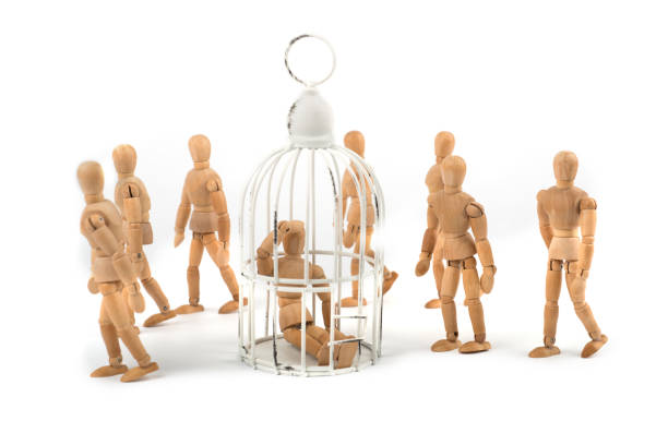 istock Wooden mannequin sits in cage in crowd - depression? helpless? ignorance? 926239318