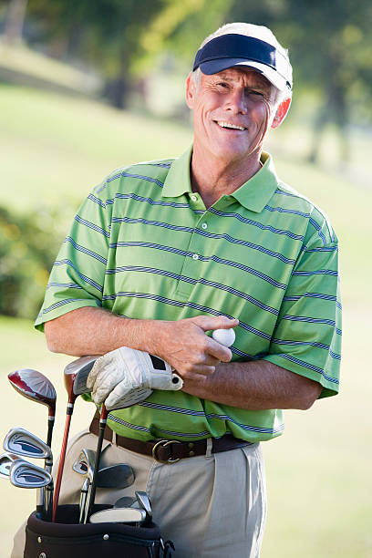 Elderly Asian male golfer is teeing off and watching his ball fly with joy and excitement on the golf course, representing active lifestyle, exercise, and health-focused outdoor activities for seniors