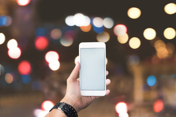 istock Closeup of man hand holding and using modern smart phone with blank screen for your text or content, with night light bokeh 926242350