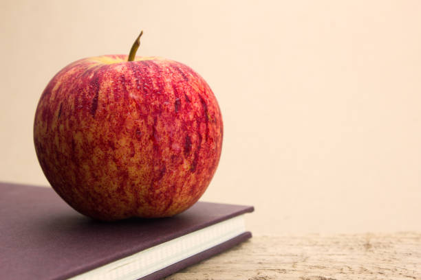 pommes rouges mis sur le livre brun comme arrière-plan - book brown apple education photos et images de collection