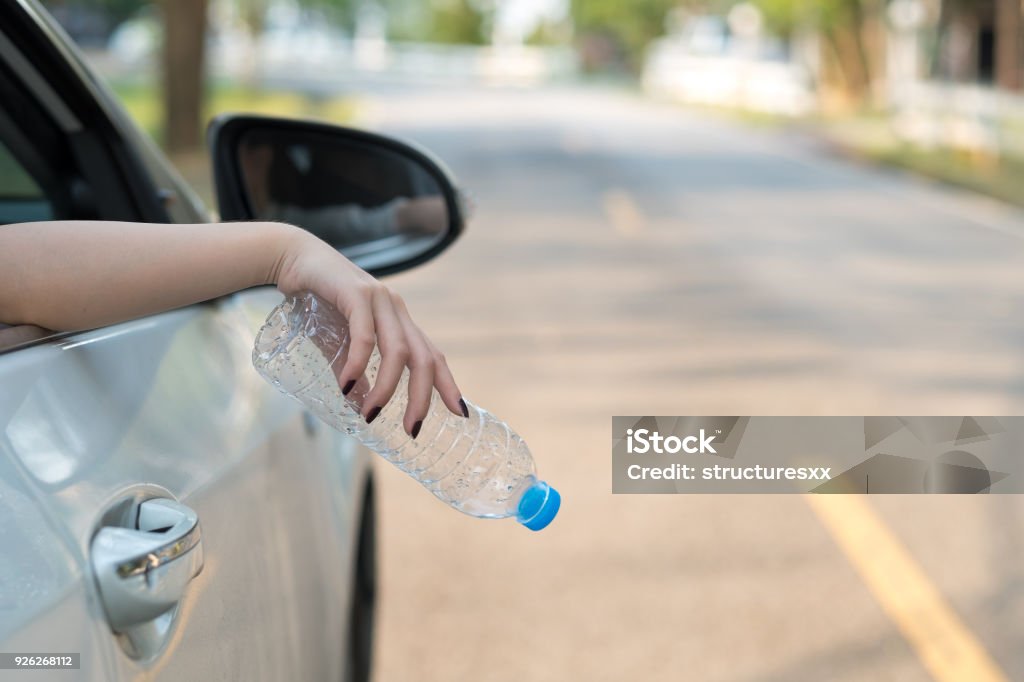 Hand throwing plastic bottle on the road Car Stock Photo