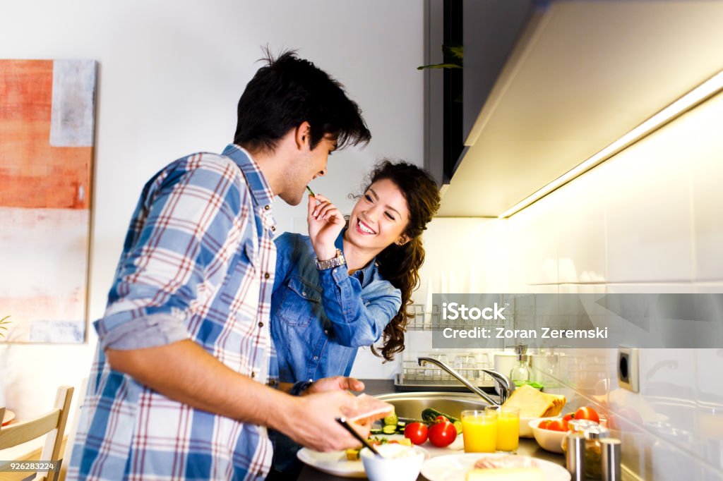 Young couple making breakfast early in the morning in the kitchen and having a good time. 20-24 Years Stock Photo