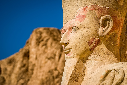 Nefertari statue, wife of Ramesses II in the temple of Luxor, Egypt, close to a palm tree in a sunny day with blue sky