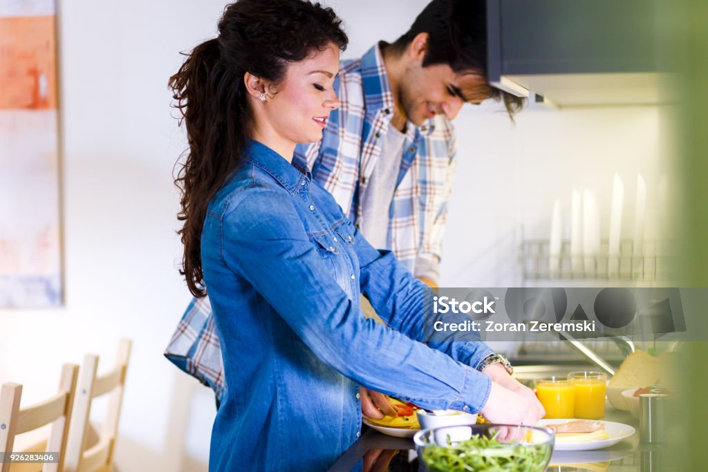 Young couple making breakfast early in the morning in the kitchen and having a good time. 20-24 Years Stock Photo