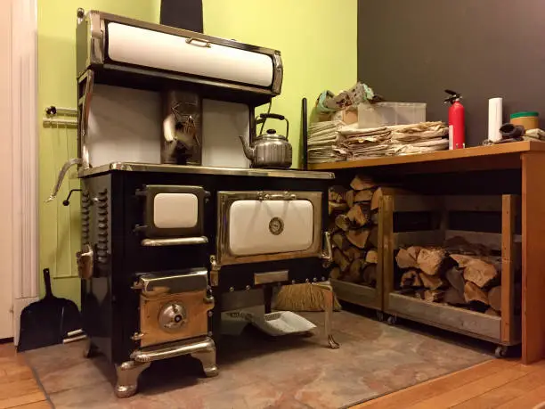 Wood burning stove with kettle next to stack of firewood