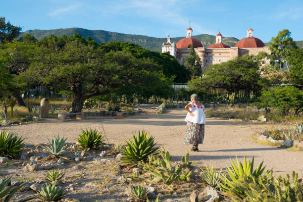 A Mexican woman walks on the grounds of the important Mesoamerican archeological site in Mitla, in the state of Oaxaca. The Church of San Pablo is visible in the background. (November 3, 2014)