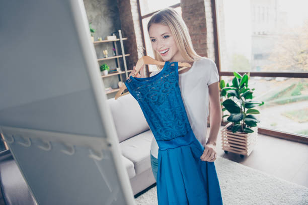 I want to wear this elegant beautiful blue dress! Pretty smiling happy excited joyful delightful blond is trying on new dress in front of a mirror I want to wear this elegant beautiful blue dress! Pretty smiling happy excited joyful delightful blonde is trying on new dress in front of a mirror dress stock pictures, royalty-free photos & images