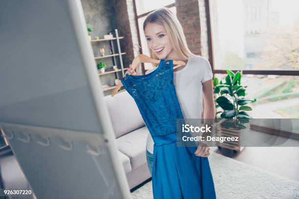 I Want To Wear This Elegant Beautiful Blue Dress Pretty Smiling Happy Excited Joyful Delightful Blond Is Trying On New Dress In Front Of A Mirror Stock Photo - Download Image Now