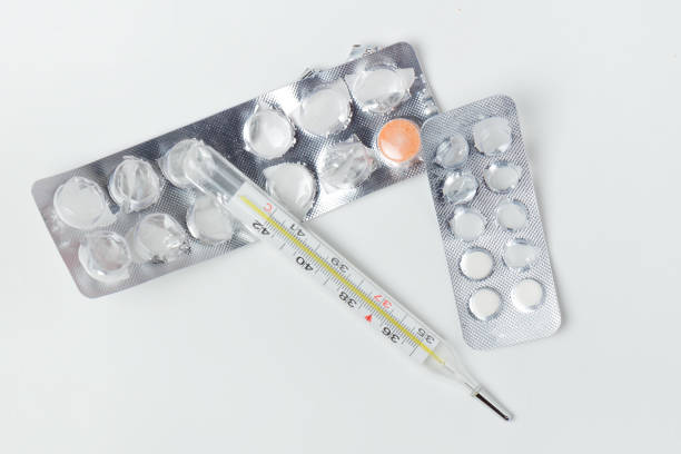 istock Thermometer and pills lie on a white background 926312398