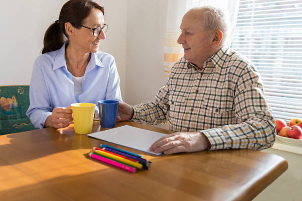 istock Home Caregiver talking with older man 926313036