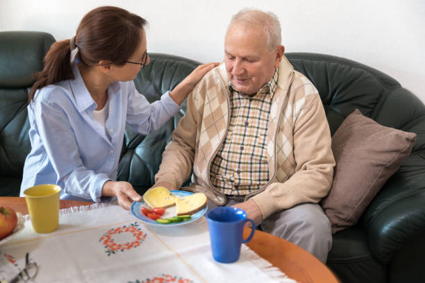 istock Home Caregiver giving senior man lunch 926313150