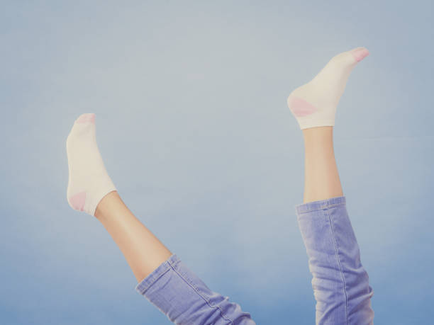 Woman feet wearing clean white socks and jeans having fun. Studio shot on blue background.