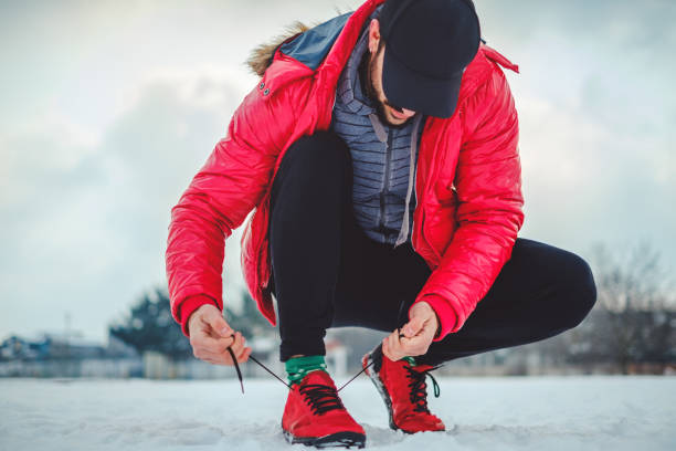 istock Man tying a right sneaker on a snowy ground 926313416