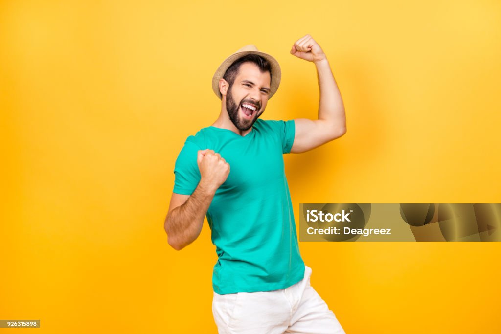 The main task is completed! Yeah! I did it! I reached so long desired success! Happy excited cheerful joyous guy celebrating his victory with raised hands, isolated on yellow background Men Stock Photo