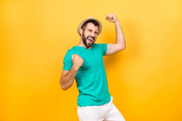 the main task is completed! yeah! i did it! i reached so long desired success! happy excited cheerful joyous guy celebrating his victory with raised hands, isolated on yellow background - ecstatic excitement arms raised men imagens e fotografias de stock