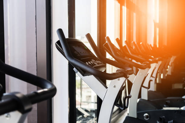 istock Modern gym interior with equipment. Row of training exercise bikes wheel detail, backlight. Healthy lifestyle concept 926324226
