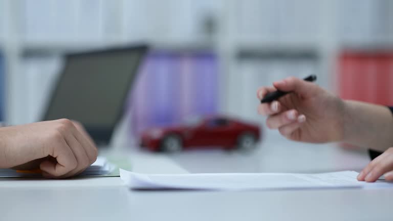 Car dealer or insurer showing a contract to a customer, model car in the background