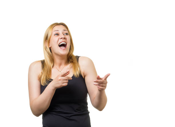 Young laughing european woman pointing by fingers against white background. Taunting on someone