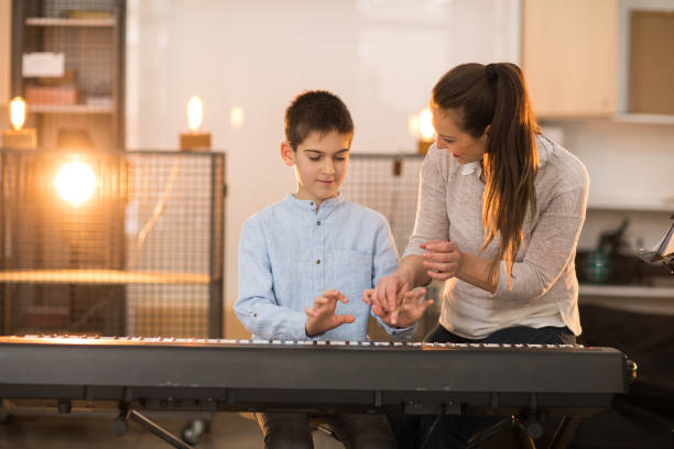istock Teacher and a boy playing stage piano indoors 926358670
