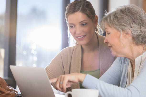 istock Woman shows senior mother how to use computer 926363080