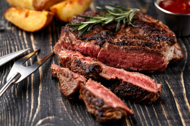 Juicy steak medium rare beef with spices on wooden board on table stock photo