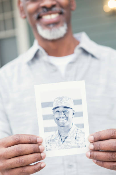 Proud father holds photo of son in the military Close up of a black and white photo of a young man serving overseas in the military. The young man's proud father is holding the photo. Focus is on the photo. veteran photos stock pictures, royalty-free photos & images