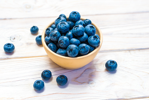 Blueberries in a wooden bowl. Top view. Ripe and tasty blueberries on a wooden background.