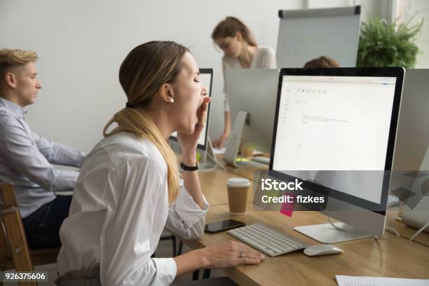 Tired Businesswoman Yawning Working On Computer Sitting At Office Desk Stock Photo - Download Image Now