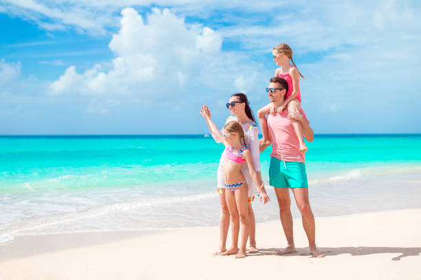 Happy beautiful family of four on white beach