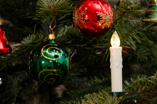 istock electric candle and christmas baubles on christmas tree 926379122