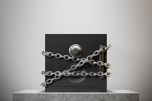 Closed safe box standing against a white wall on a marble table. Chains. Concept of security and economics. 3d rendering mock up