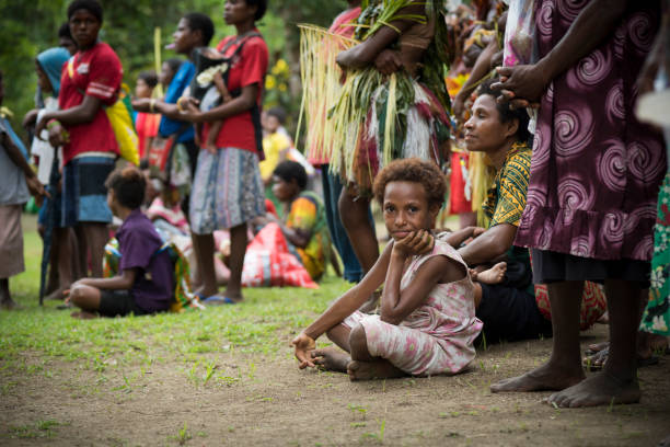 A young girl sits on the ground during a celebration in Tambapmining, a village on the lower Ramu River in Madang Province, Papua New Guinea (2017)