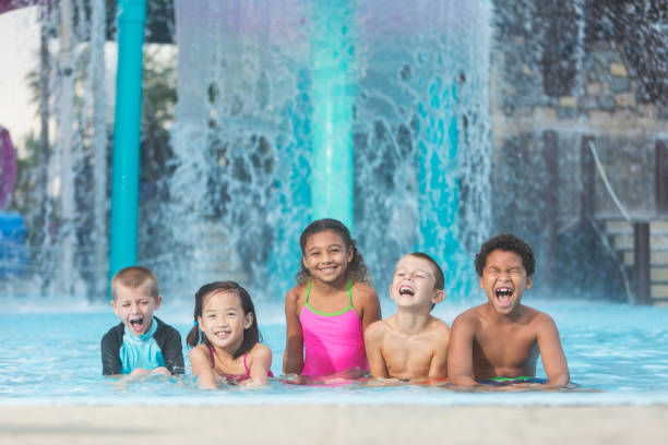 grupo de niños y multiétnicos en la piscina del parque acuático - swimming pool water people sitting fotografías e imágenes de stock